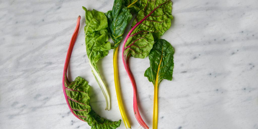 five green spinach leaves on white surface