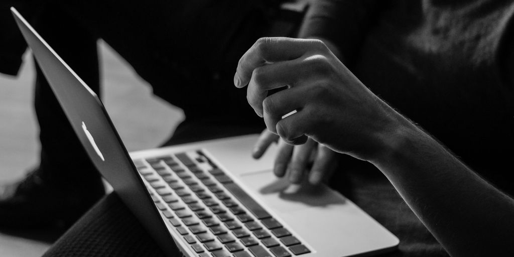 grayscale photo of person using MacBook